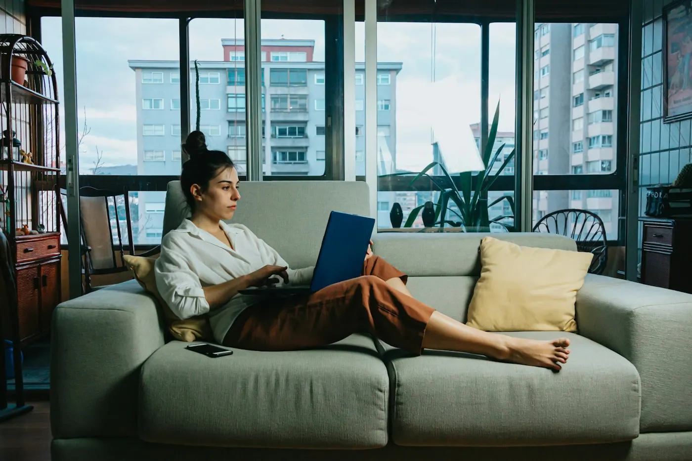 Mulher relaxando no sofá de casa com o notebook
